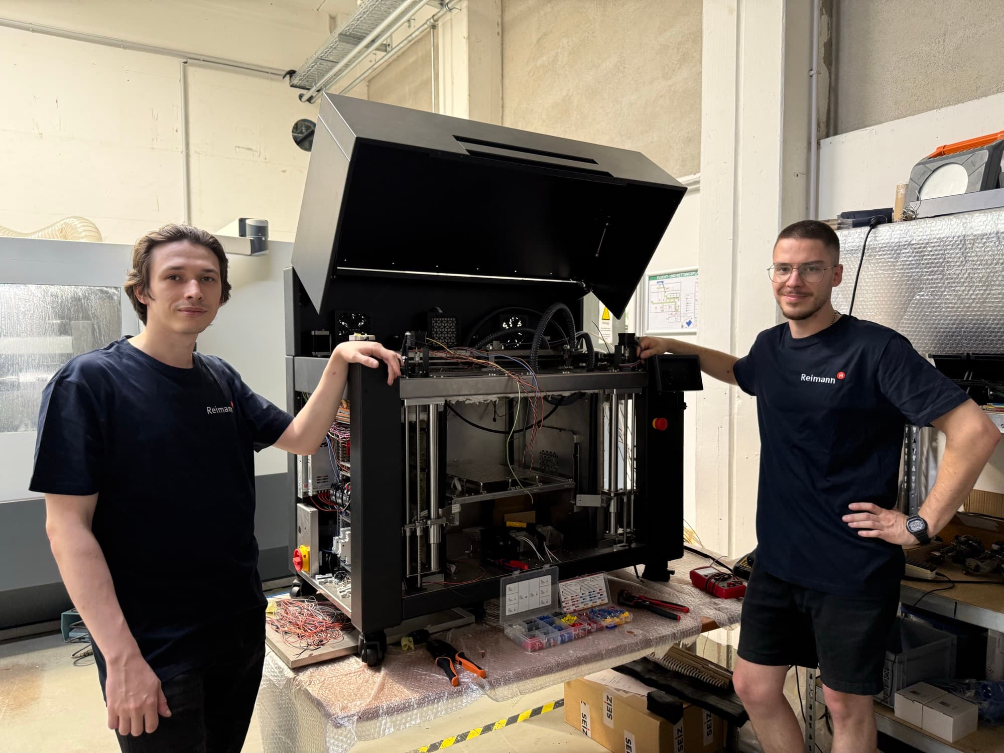 Two Reimann engineers assembling a Heron 3D printer